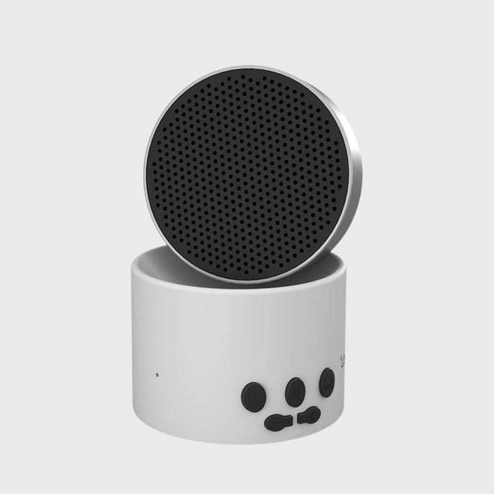 Circular speaker resting atop a cylindrical base with control buttons, against a plain background.