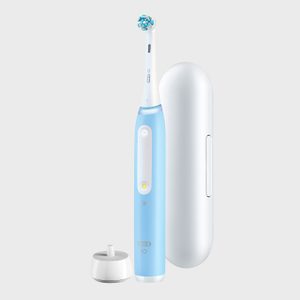 Electric toothbrush stands upright beside charging stand and travel case, against a plain background.