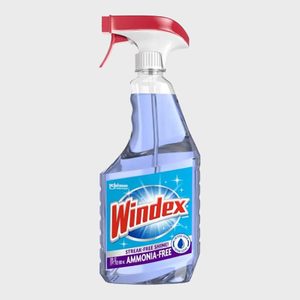 A spray bottle of Windex stands upright, filled with blue liquid, featuring a red nozzle against a plain gray background.