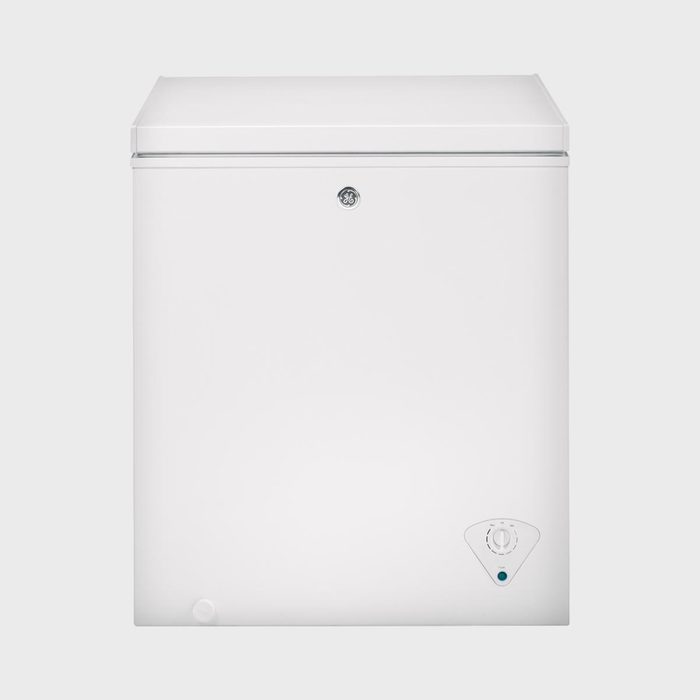 White chest freezer appears closed, displaying a temperature control dial at the bottom corner, against a plain background.