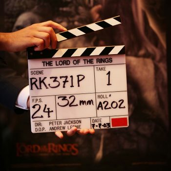 Clapperboard displays "The Lord of the Rings," held by a hand, with scene details against an out-of-focus background. Text includes scene, take, and date.