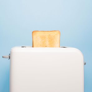 A slice of toasted bread pops up from a white toaster against a blue background.
