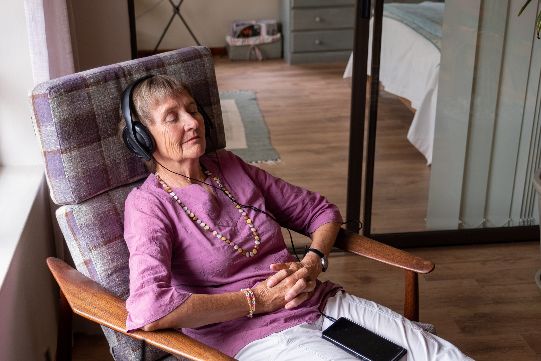 Senior woman sits and relaxes with music in her ears