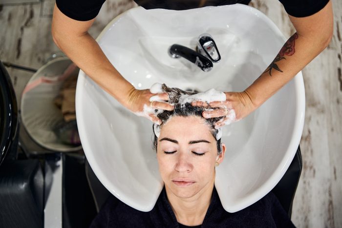 Hairdresser lathers client's hair.