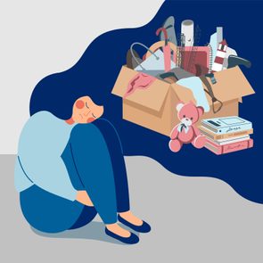 Person huddled sadly, sitting beside a box filled with various personal items like books and a teddy bear, indicating a sense of loss or change.