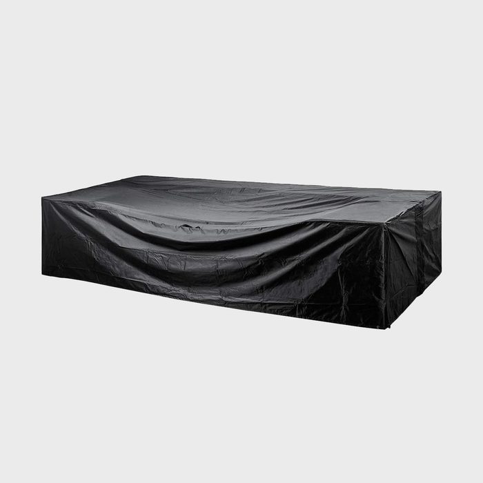 A large rectangular black cover drapes over a low, rectangular object on a plain gray background.