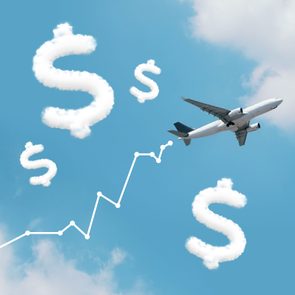 Airplane flies through blue sky with cloud dollar signs and an upward trend line in the background.