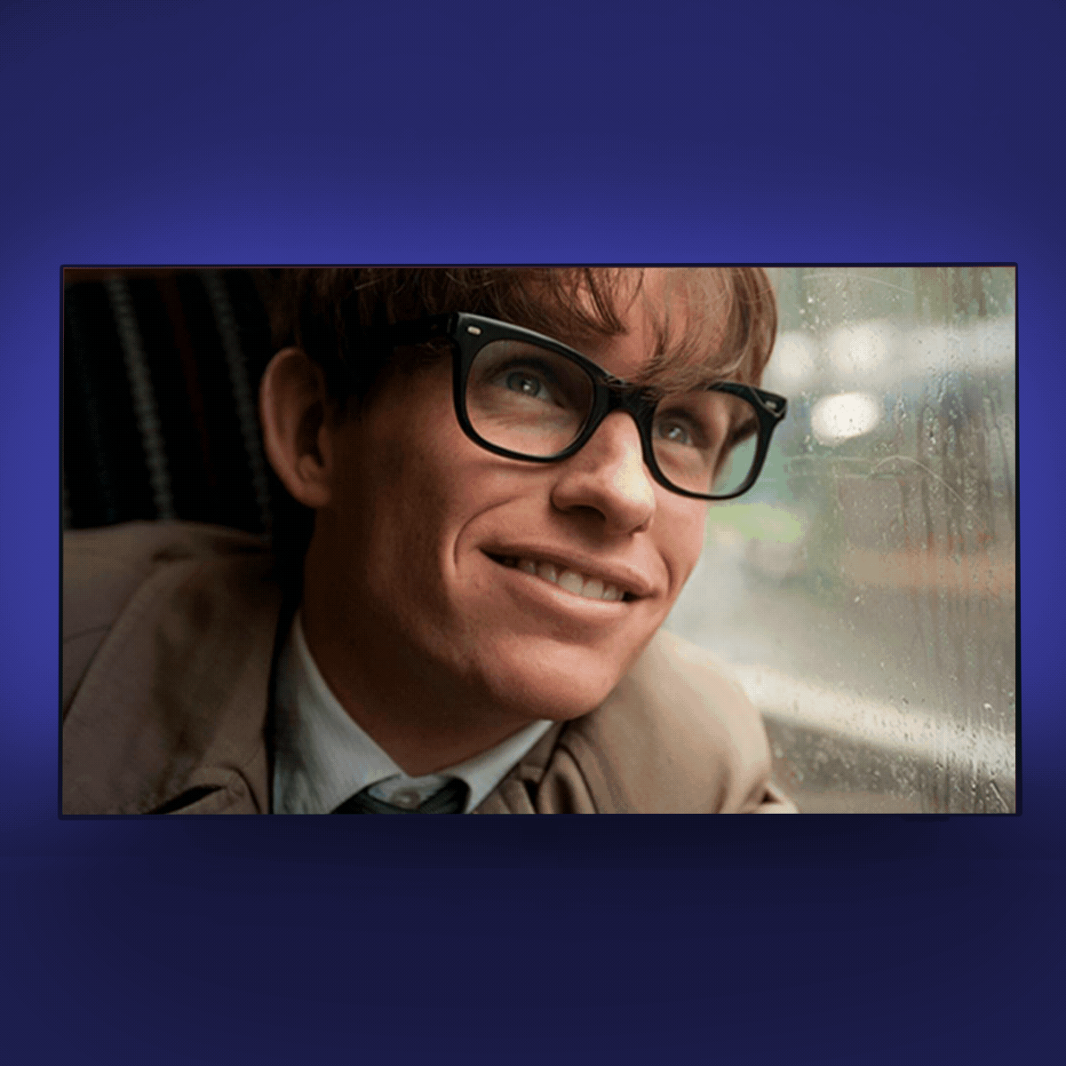 A person smiles while looking out a rainy window, seated in a dimly lit space with an atmosphere of contemplation.