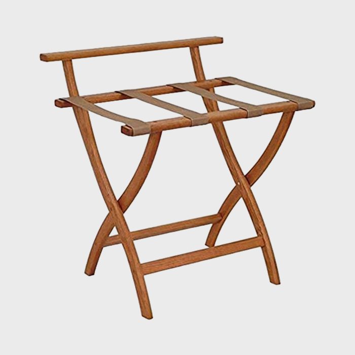 Wooden luggage rack stands open, featuring crossed legs and sturdy fabric straps, set against a plain white background.