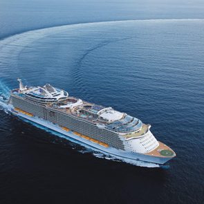 Cruise ship makes wide turn, leaving a curved wake in expansive ocean.