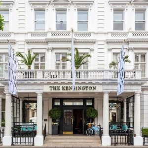 Hotel entrance displays flags outside, surrounded by tall white columns and potted plants; 