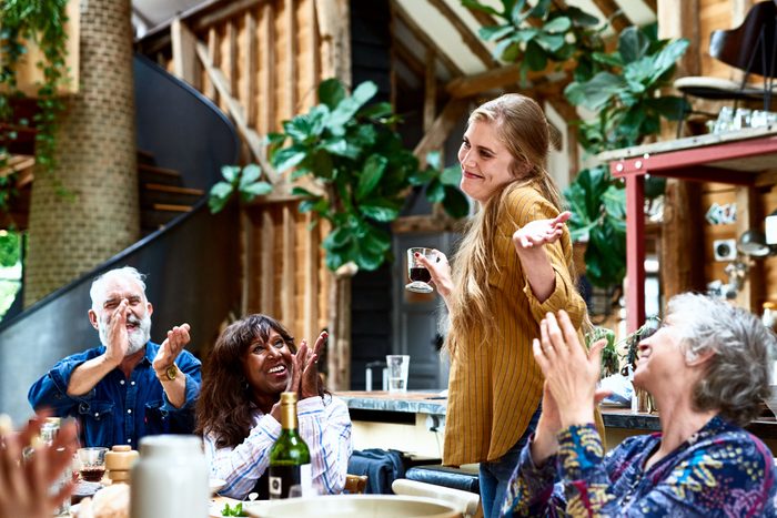 Cheerful woman making speech at party smiling and shrugging