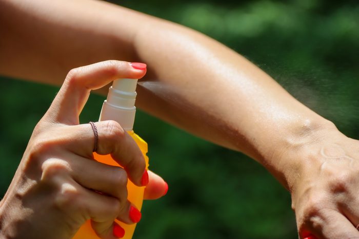 Person spraying mosquito insect repellent in the forest, insect protection