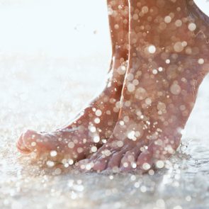 Feet splash water on a sunlit, shimmering surface.