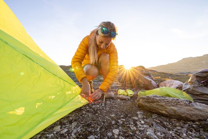 Woman setting up tent outdoors in Norway