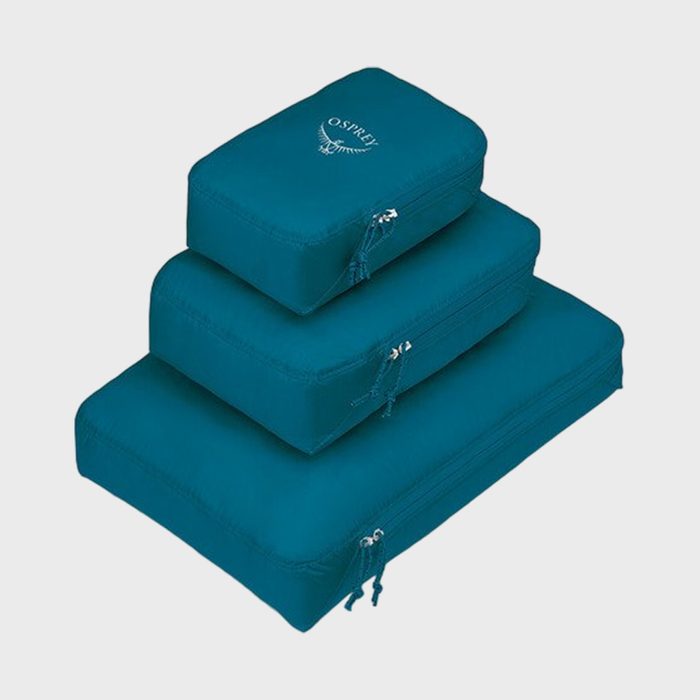 Three teal packing cubes stacked, featuring zippers; top cube reads 