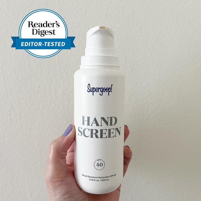 A hand holds a white bottle labeled 