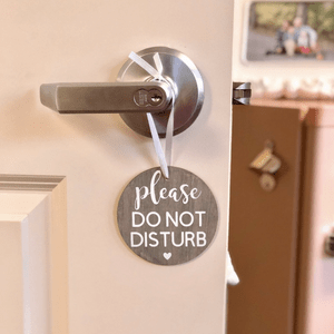 A round sign hangs on a silver door handle, reading 