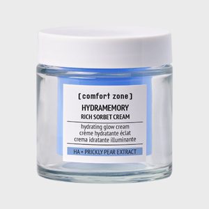 A glass jar with a white lid contains blue cream labeled 