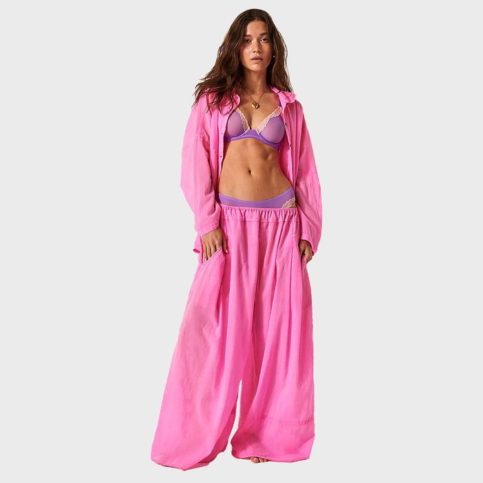 A person wears a bright pink outfit and lavender underwear against a plain white background.