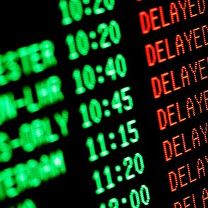 Departure board displays flight times in green and status as 