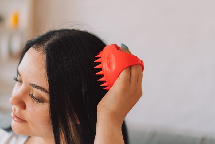 Lady with scalp massager in her hands makes herself massage
