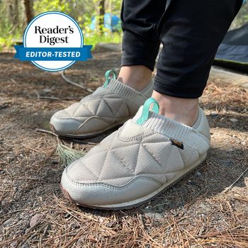 Quilted slip-on shoes are worn on pine needle-covered ground, next to "Reader's Digest Editor-Tested" badge.
