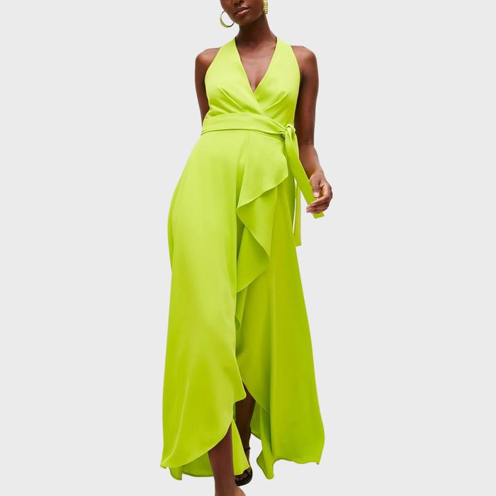 Woman wearing a bright green wrap dress stands confidently against a plain white background.