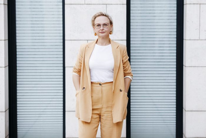 fashionable woman standing with hands in her pockets, shirt is tucked in
