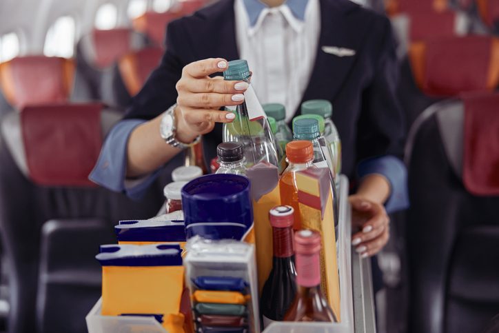 Stewardess take water bottle from trolley cart