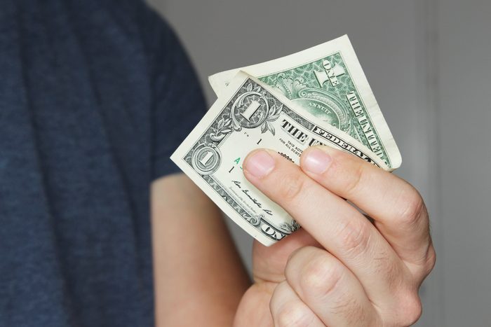 A white male holding a one dollar note.