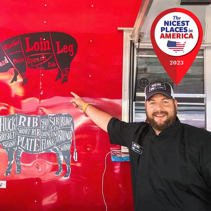 Man points at meat cuts diagram on a bright red food truck wall; 