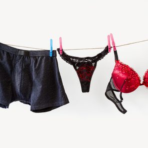 Underwear hangs on a clothesline, secured by colorful clothespins, set against a plain white background.