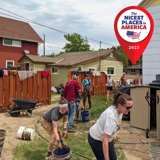 People work together outside; some carry buckets near a fence in a residential backyard. Text: 