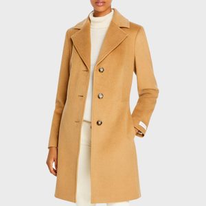 Camel-colored coat worn by a standing person, set against a plain light background.