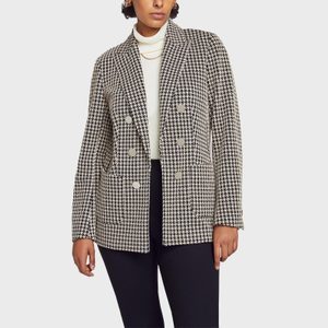 A person wears a houndstooth blazer and black pants against a plain background.