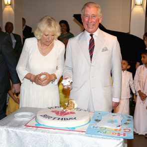 Cake being cut by a man in a light suit, indoors, with people around. Cake reads 