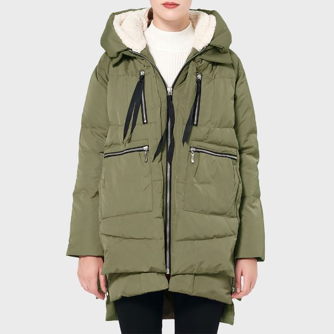 Green puffer jacket with a hood and black drawstrings, worn over a white turtleneck, displayed against a plain gray background.