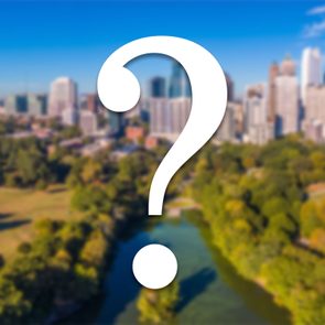 Question mark overlays blurred city skyline and park landscape, under a blue sky.