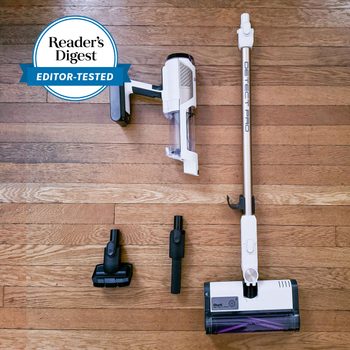 Vacuum cleaner lies disassembled on a wooden floor, surrounded by attachments. A "Reader's Digest Editor-Tested" badge appears in the corner.