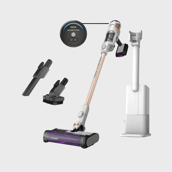 Vacuum cleaner stands upright, accompanied by accessories and a charging station. Display screen shows 