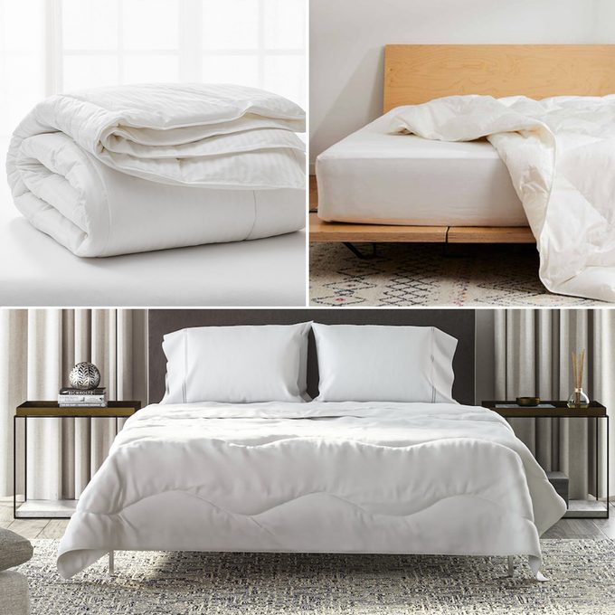 A white comforter lies neatly folded, draped over a wooden bed, and spread across a well-made bed in a modern bedroom setting.