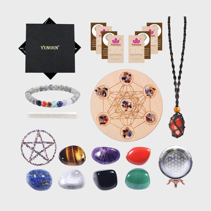 Jewelry and crystals are arranged with a bracelet, necklace, stones, and a decorated circular wooden board, displayed against a plain background.