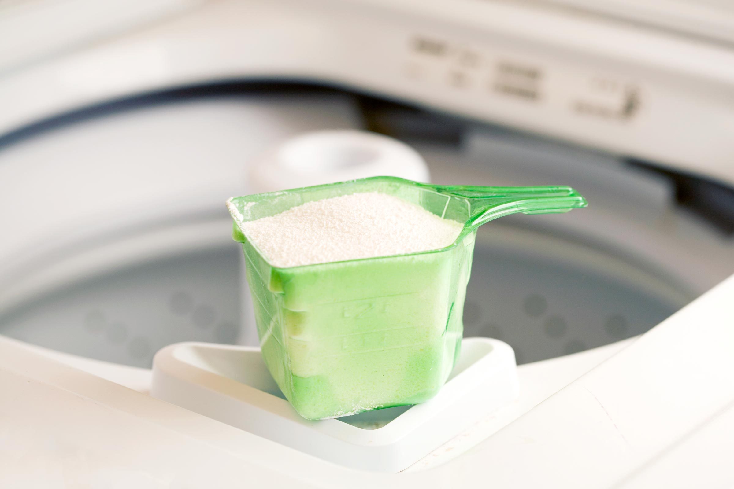 borax cup resting on the edge of a top loading washing machine