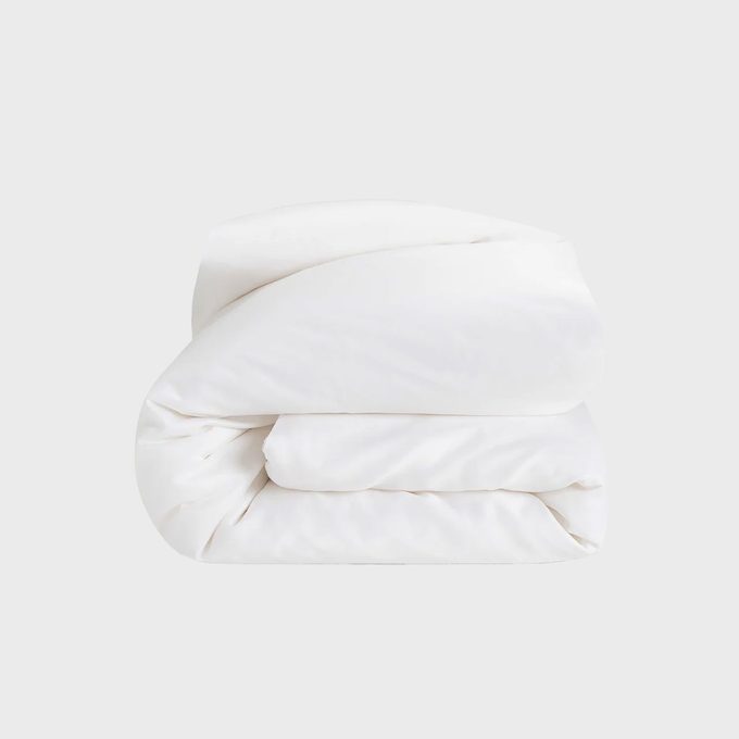 White comforter neatly folded against a plain, light gray background.