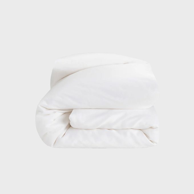 A white comforter is neatly folded against a plain, light gray background.