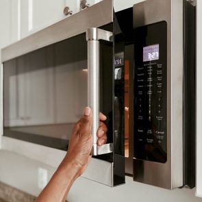 Hand opens microwave door; time display reads 