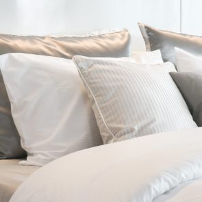 Cushions rest on a bed with white sheets, creating a calm and cozy bedroom ambiance.