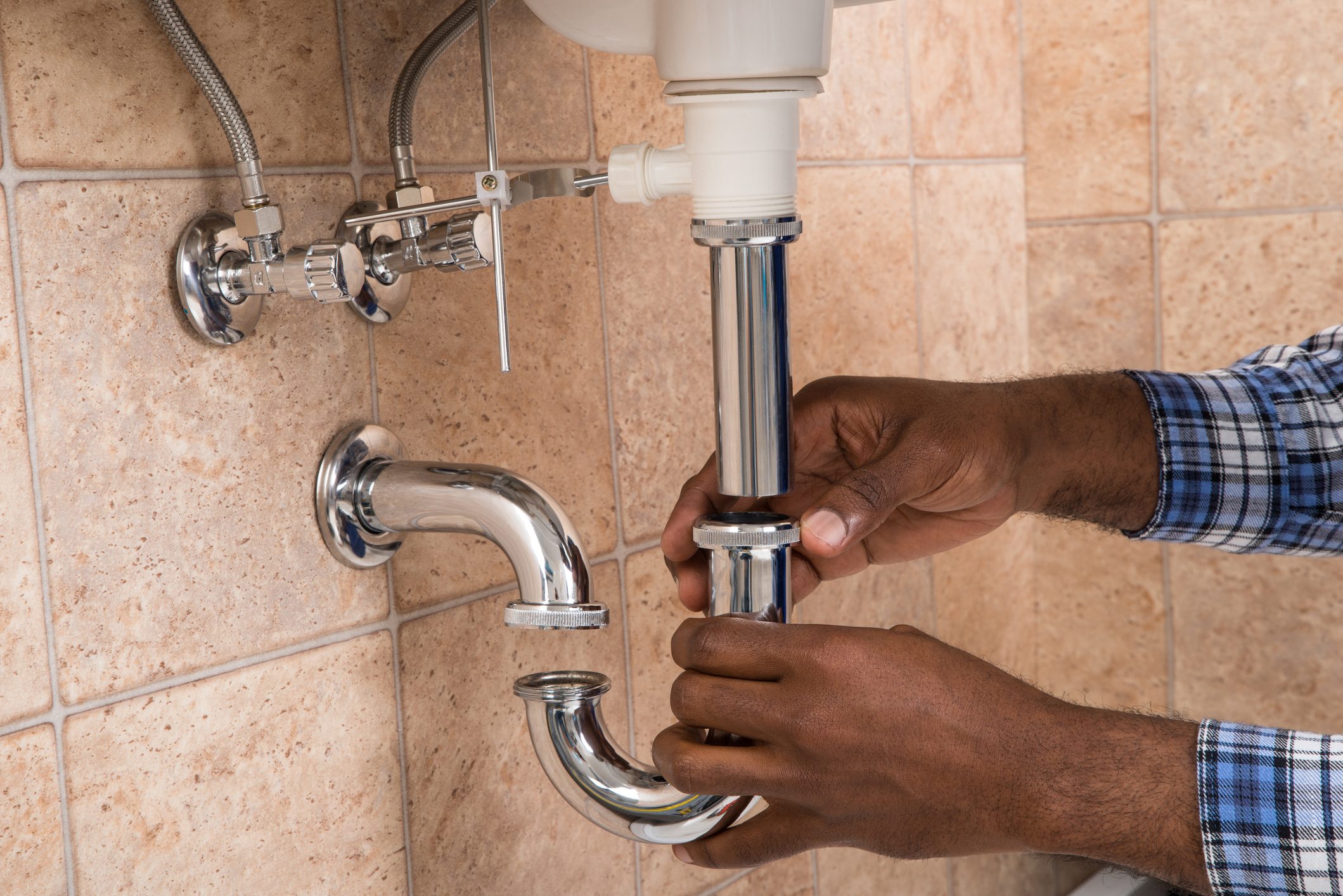 Plumber's Hand Fixing Sink In Bathroom
