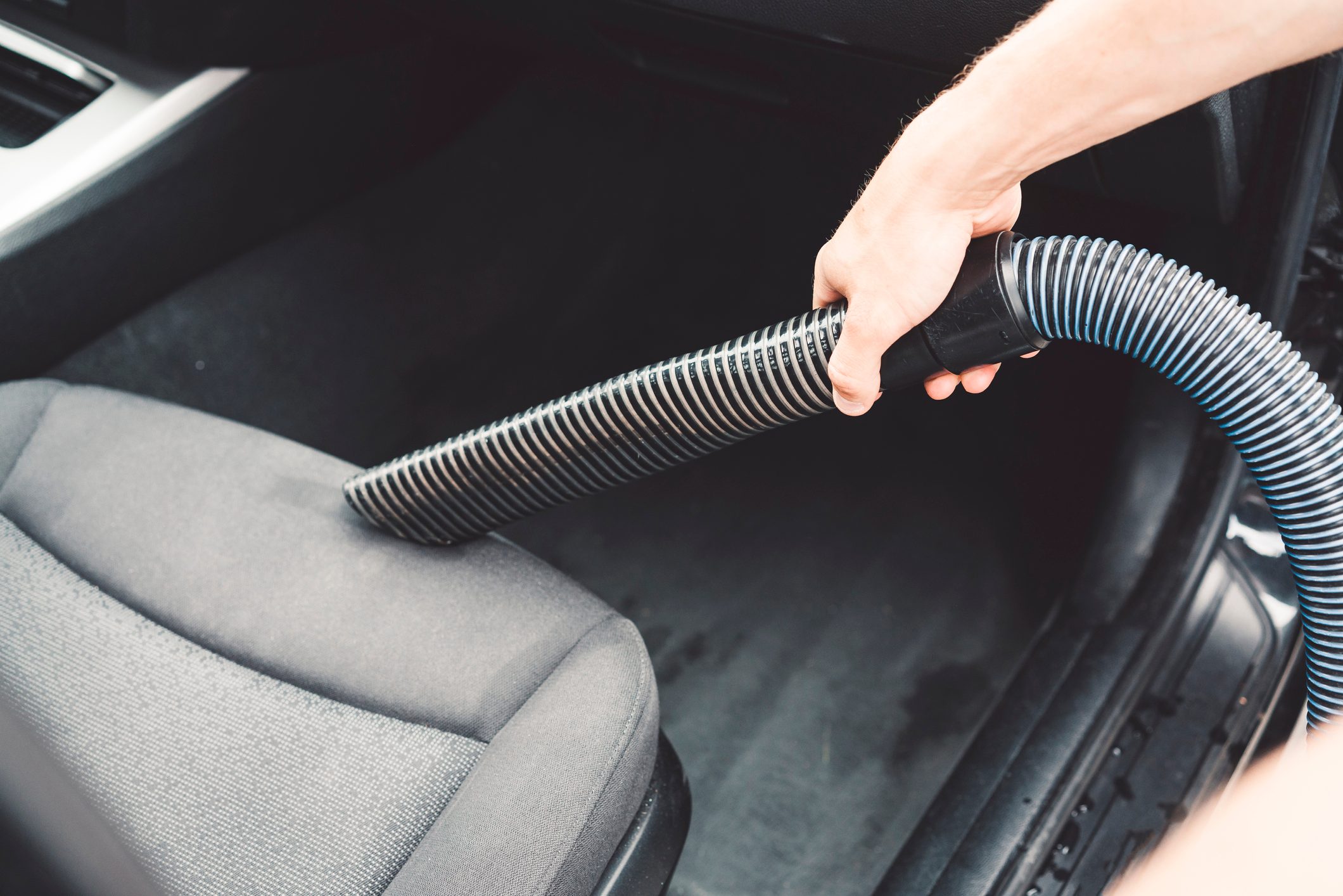 Man is vacuuming the seats inside of his car